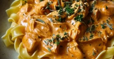 Cremiges Hähnchenragout mit Bandnudeln auf einem Teller angerichtet.