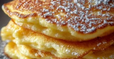 Fluffige Apfelpfannkuchen auf einem Teller, serviert mit Zimt und Zucker.